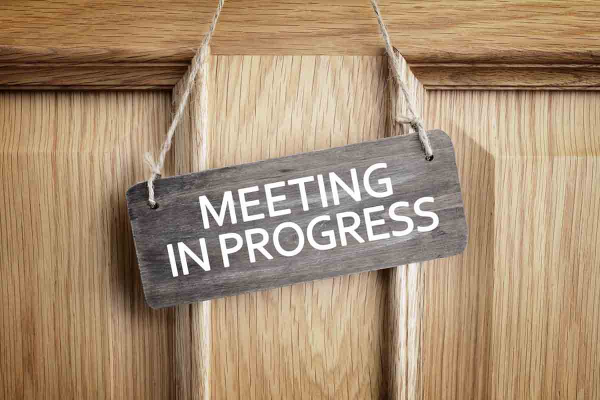 Sign on an office door that says meeting in progress
